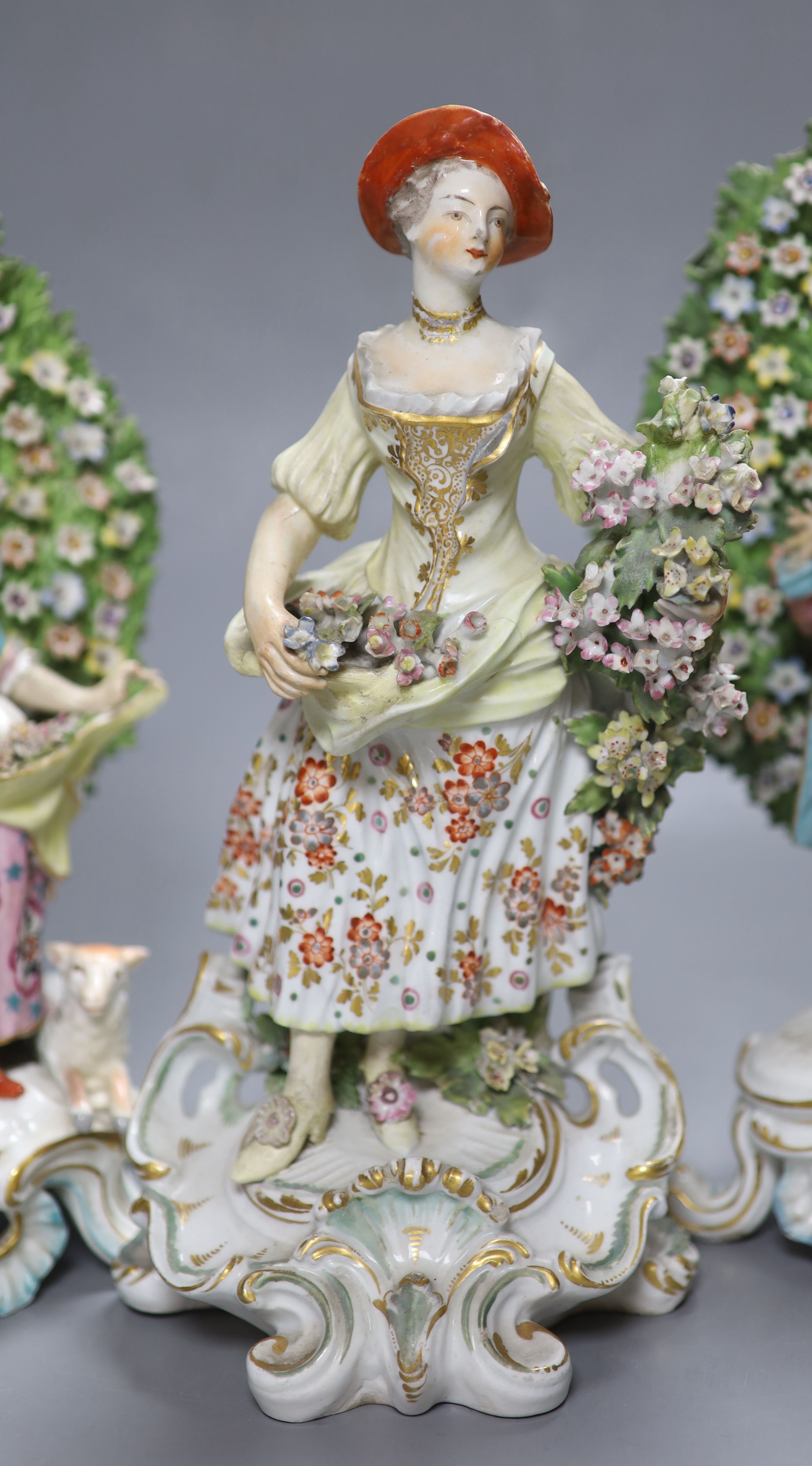 An 18th century Derby figure of a flower seller and a pair of French porcelain bocage groups, tallest 27cm